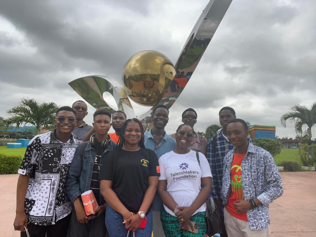Scholars and staff grouped in front of a park sculpture